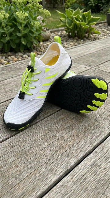White and black athletic shoe with green accents on a wooden surface